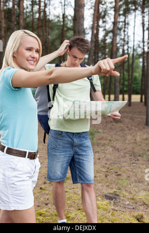 Giovane donna rivolto lontano con confuso uomo azienda mappa forest Foto Stock