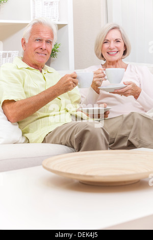 Felice senior l uomo e la donna giovane seduti insieme a casa su un divano a bere tazze di tè o caffè Foto Stock