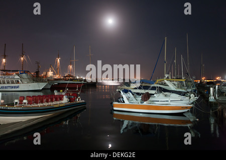 Una luna piena in un cielo chiaro illumina il porto a Yalikavak, Turchia. Imbarcazioni da diporto riposo dopo una giornata di lavoro. Foto Stock