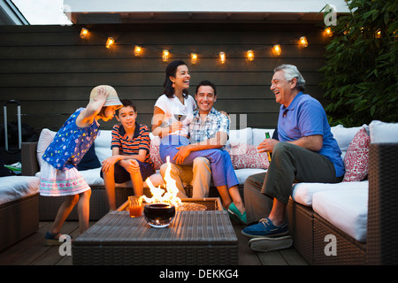 Famiglia relax intorno una buca per il fuoco all'aperto Foto Stock