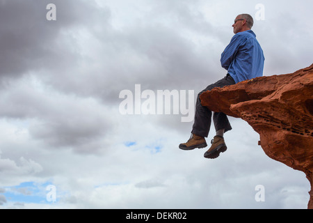 Uomo caucasico seduto sul bordo scogliera Foto Stock