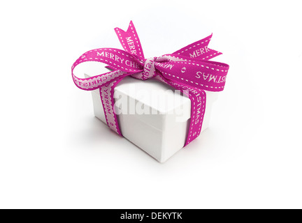 Avvolgere un regalo di Natale con un colorato nastro rosa e la prua su uno sfondo bianco. Foto Stock