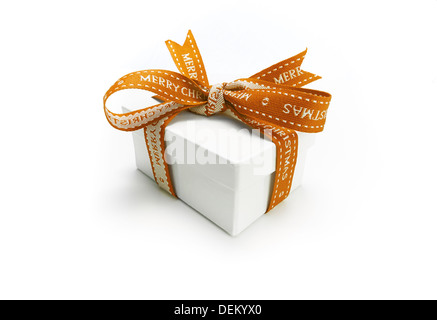 Avvolgere un regalo di Natale con un colorato nastro color oro e la prua su uno sfondo bianco. Foto Stock