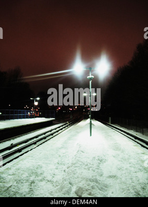 La piattaforma del treno e le vie coperte di neve durante la notte Foto Stock