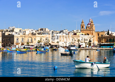 Due uomini in barca a remi al porto di Marsaxlokk, Malta. Foto Stock