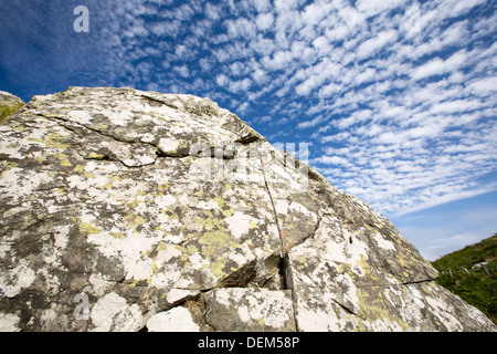 I modelli cloud al di sopra di un lichene coperto sul rock Cornish Coast vicino Zennor, UK. Foto Stock