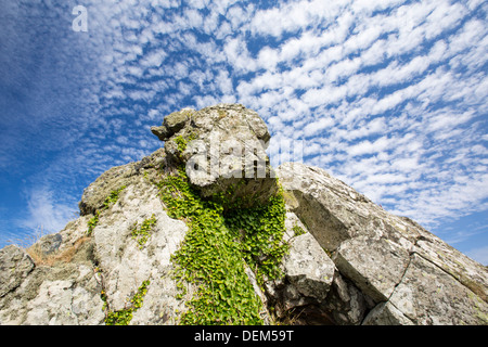 I modelli cloud al di sopra di un lichene coperto sul rock Cornish Coast vicino Zennor, UK. Foto Stock