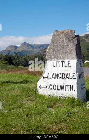 Primo piano del cartello stradale in pietra milestone Colwith e Little Langdale Pikes sullo sfondo in estate Cumbria Inghilterra Regno Unito Gran Bretagna Foto Stock