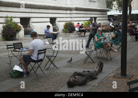 Senzatetto uomo dorme sul marciapiede sulla terrazza al New York Public Library, 5 Ave. & 42Nd St. NYC. Foto Stock