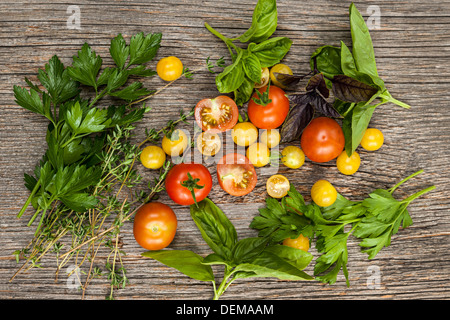 Freschi pomodori colorati e le erbe sul rustico sfondo di legno dal di sopra Foto Stock