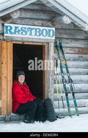 Donna seduta al di fuori del rifugio sciistico, Svezia. Foto Stock