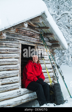 Donna seduta al di fuori del rifugio sciistico, Svezia. Foto Stock