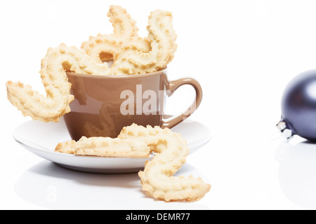 Natale spritz i cookie in un marrone tazza da caffè su sfondo bianco Foto Stock