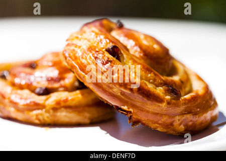 Due acquolina in bocca a scaglie sultana pasticceria danese è su una piastra, all'esterno, su un tavolo al sole Foto Stock