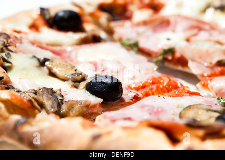 Pane appena sfornato la pizza con un prosciutto, funghi e olive topping servita all'aperto su una luminosa giornata di sole Foto Stock