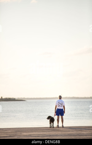 Un uomo con il suo cane lungo waterfront park nel quartiere storico di Charleston, Sc. Foto Stock