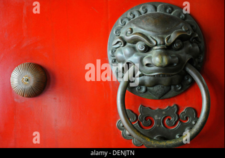 Una porta ornata respingente nella forma di un feroce guerriero sulla parte anteriore di un chiodati porta rossa. Foto Stock