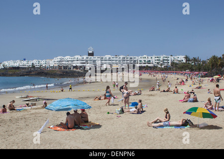 Turisti sulla sabbia a Playa de las Cucharas, Costa Teguise, Lanzarote, Isole Canarie, Spagna. Un popolare resort di Lanzarote Foto Stock