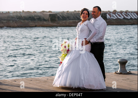 Una giovane coppia il loro giorno di nozze che è fotografata al vecchio porto di Jaffa in Israele Foto Stock