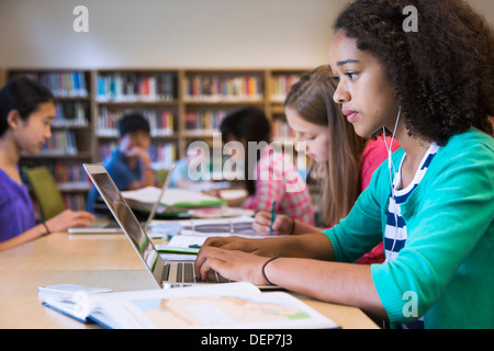 Studente utilizzando laptop in biblioteca Foto Stock