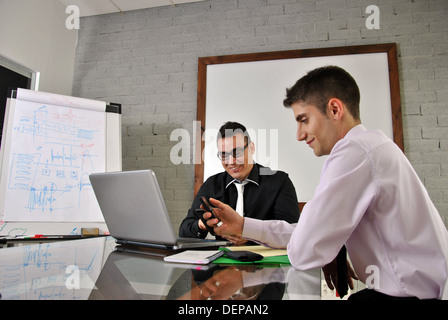 Due imprenditori seduta nel suo ufficio con il suo computer strategizing Foto Stock