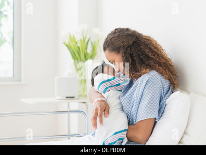 Madre ispanica tenendo il neonato in ospedale Foto Stock