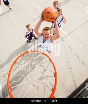 Caucasian ragazzi giocare a basket su corte Foto Stock