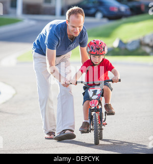 Padre caucasica figlio di insegnamento per guidare la bicicletta Foto Stock