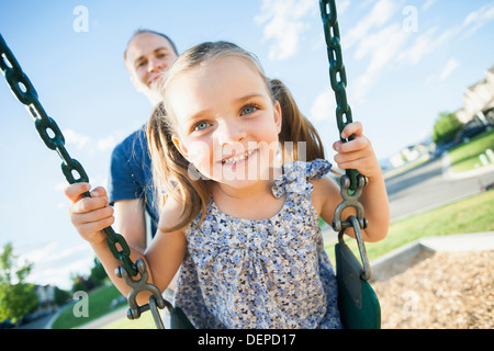 Padre caucasica spingendo la figlia per rotazione Foto Stock