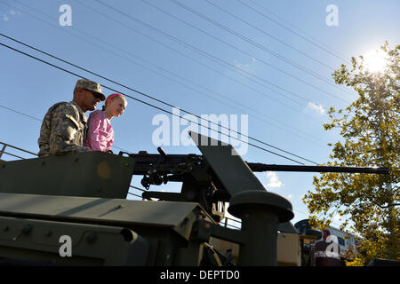 Bellmore, New York, Stati Uniti Il 22 settembre 2013. Una ragazza giovane e soldato dell'esercito sedersi nella parte superiore di un serbatoio di blindati presso l'Expo militare al ventisettesimo Bellmore annuale Festival, che offre divertimento per tutta la famiglia con mostre e attrazioni in un 25 blocco quadrato area, con oltre 120.000 persone che dovrebbero partecipare nel corso del fine settimana. Credito: Ann e Parry/Alamy Live News Foto Stock