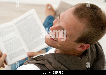 Uomo bello rilassarsi sul divano con un libro Foto Stock