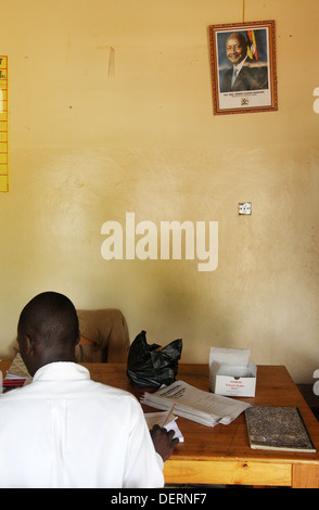 Un insegnante della scuola si siede sotto un ritratto di Uganda il Presidente Yoweri Museveni in Mawale area del distretto di Luwero in Uganda Foto Stock