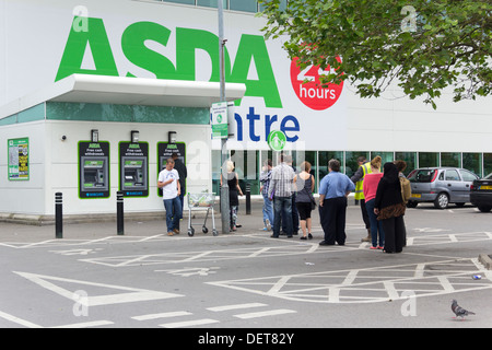 Lunga coda di persone in attesa di utilizzare lo sportello bancomat presso la ASDA Eastlands, Supercenter, Manchester. Foto Stock