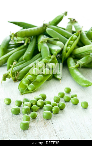 Un mucchio di fresco verde piselli, alcuni sgusciate e alcuni ancora nei loro baccelli. Foto Stock