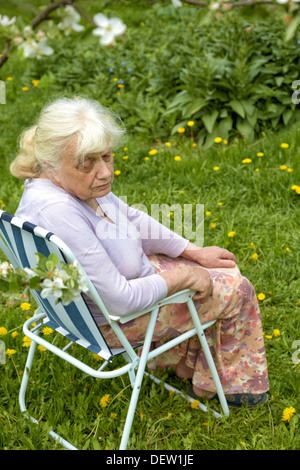 La nonna in giardino sotto una fioritura del melo Foto Stock