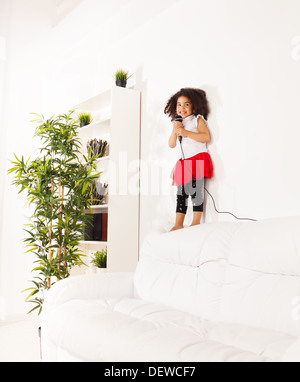 Carino piccolo Africano nero tre anni ragazza con ricci cute capelli neri con microfono di eseguire in piedi sul pullman Foto Stock