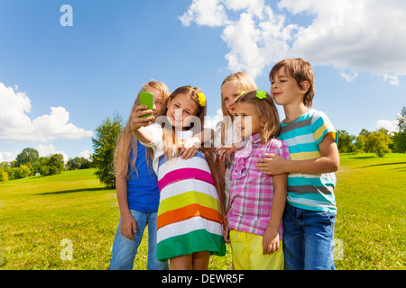 Gruppo di molti bambini, ragazzi e ragazze di scattare una foto di amici con lo smartphone in piedi insieme nel parco Foto Stock