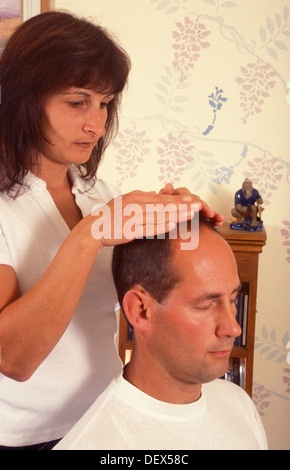 Donna dando reiki guarigione sull uomo da casa Foto Stock