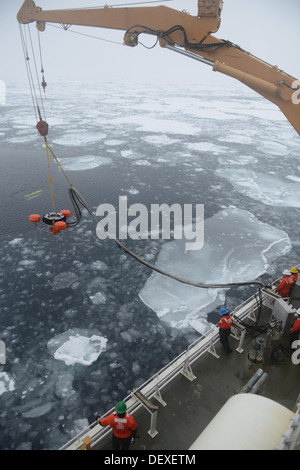 Membri del guardacoste Healy coperta inferiore di uno sfioratore dell'olio nel ghiaccio-laden Beaufort Sea durante la simulazione di una Foto Stock