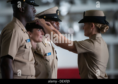 Capo Hospital Corpsman Tarren Windham sorge presso l'attenzione come la sua combinazione coperchio è posto sul suo capo da Senior Chief la comunicazione di massa specialista Monica Nelson durante una cerimonia di pinning in hangar bay a bordo della portaerei USS Carl Vinson ( Foto Stock