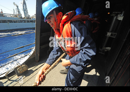 Cryptologic tecnico (tecnico) 2a classe David Aguilera heaves una linea a bordo guidato-missile destroyer USS Ramage (DDG 61) durante un rifornimento in mare con la forza militare di comando Sealift flotta oliatore di rifornimento USNS Leroy Grumman (T-AO 195). Rama Foto Stock