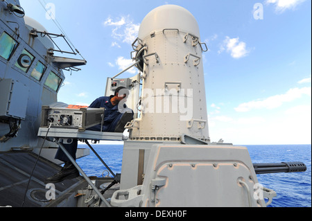 Fire Controlman 1a classe Haneef Manboard esegue le operazioni di manutenzione su un vicino-in sistema di armi (CIWS) a bordo guidato-missile de Foto Stock