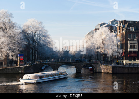 Tourist canal cruise giri in barca da fiume Amstel sul canale Herengracht canal su un freddo inverno mattina. Amsterdam, Paesi Bassi. Foto Stock