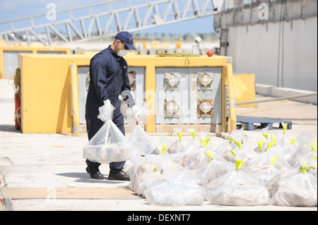 Un membro dell'equipaggio di stanza a bordo del guardacoste posti in avanti di un sacco di cocaina sequestrati insieme con il resto Venerdì, 20 settembre 2013, alla Naval Station Mayport, Fla. i farmaci sono stati sequestrati da una guardia costiera dell'applicazione della legge il distacco di stanza a bordo Foto Stock