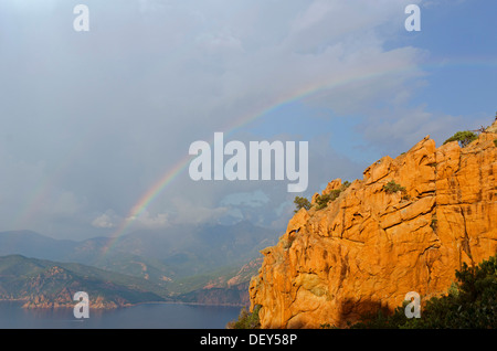 Il bizzarro tipiche rocce rosse delle Calanche di Piana e il mare mediterraneo nel golfo di Porto in background al di sotto di un Foto Stock