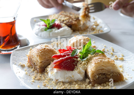 Il Baklava coppie ben calda con tè turco e servita con Fragola e pieno di grasso di crema e guarnite con foglie di menta Foto Stock