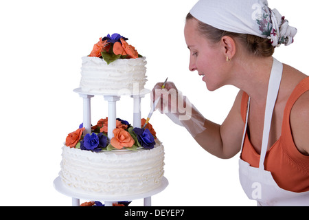 Baker lady dando ad una torta di nozze ultime piccoli ritocchi, torta ha fondente volant sul lato e decorate con arancia e p Foto Stock