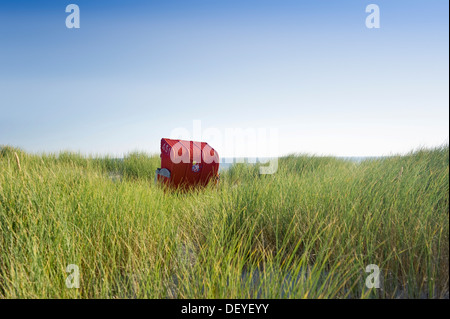 Rosso con tetto di vimini sedia spiaggia di dune di sabbia, Amrum, Amrum, Nord Isole Frisone, Schleswig-Holstein, Germania Foto Stock