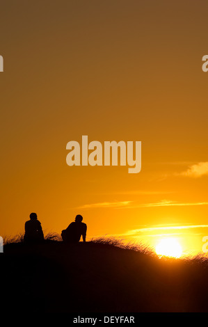 Silhouette di due persone nelle dune al tramonto, Nebel, Amrum, Amrum, Nord Isole Frisone, Schleswig-Holstein, Germania Foto Stock