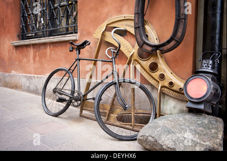 Lanterna e vecchio ciclo nero appoggiarsi contro la parete Foto Stock